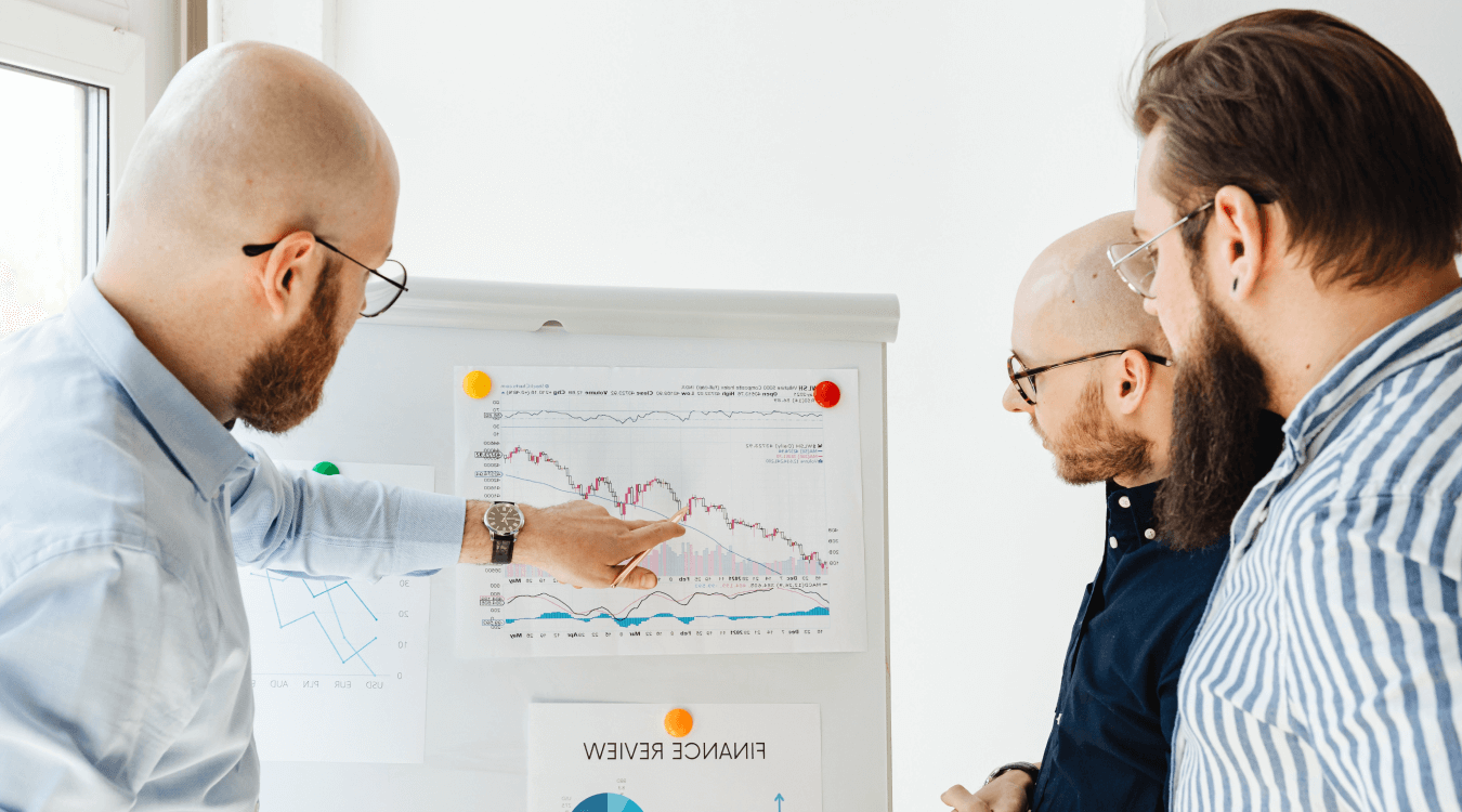 Three businessmen looking at graphs during a finance review to reconsider their spending