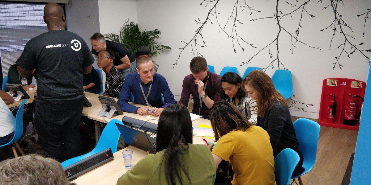 A group of people gathered around a table in discussion at CodeUntapped